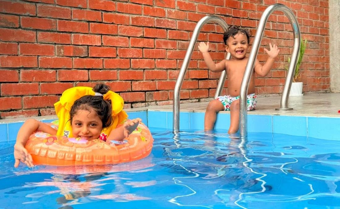 Two children playing in the pool against a brick wall